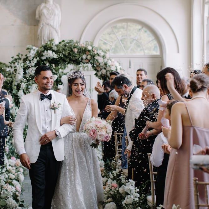 Bride in Berta Bridal wedding dress and Groom in white dinner jacket walking up the aisle as husband and wife