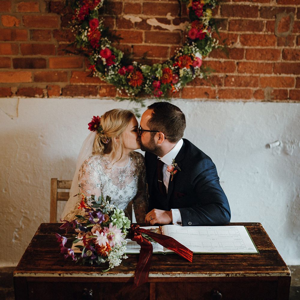 Bride in Bead Embellished Needle &amp; Thread Gown with Cascading Tulle Skirt and Semi Sheer Sleeves | Elbow Length Veil | Bridal Up Do with Pink Hair Flowers | Groom in Check Blue Three Piece Suit by T.M.Lewin with Maroon Tie and Pocket Square | Purple, Orange and Pink Flowers with Foliage and Maroon Trailing Ribbon | Floral Wreath Altar | Rustic Bureau | Signing of the Register | Mariachi Band and Persian Rug Aisle for Autumn Wedding | Leah Lombardi Weddings