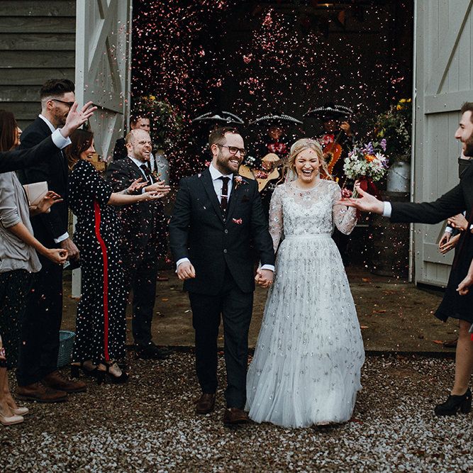 Bride in Bead Embellished Needle &amp; Thread Gown with Cascading Tulle Skirt and Semi Sheer Sleeves | Elbow Length Veil | Bridal Up Do with Pink Hair Flowers | Groom in Check Blue Three Piece Suit by T.M.Lewin with Maroon Tie and Pocket Square | Purple, Orange and Pink Flowers with Foliage and Maroon Trailing Ribbon | Confetti Moment | Mariachi Band and Persian Rug Aisle for Autumn Wedding | Leah Lombardi Weddings