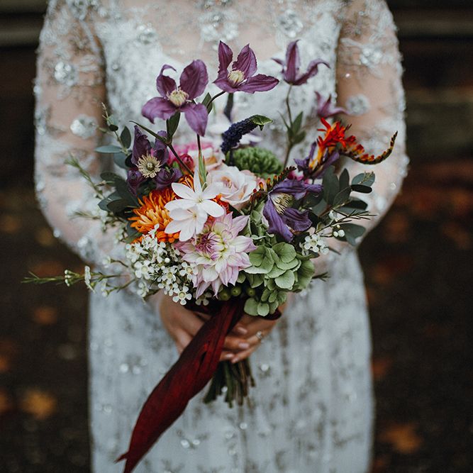 Purple, Orange and Pink Flowers with Foliage and Maroon Trailing Ribbon | Bride in Bead Embellished Needle &amp; Thread Gown with Cascading Tulle Skirt and Semi Sheer Sleeves | Mariachi Band and Persian Rug Aisle for Autumn Wedding | Leah Lombardi Weddings