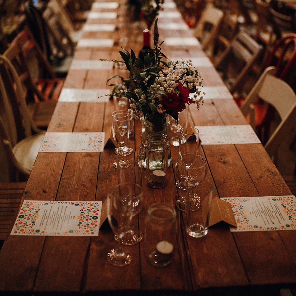 Wooden Banquet Tables | Mismatched Rustic Chairs | Tea Lights in Jars | Kraft Place Settings | Wedding Breakfast Menus | Red and White Flowers and Foliage Centrepieces | Mariachi Band and Persian Rug Aisle for Autumn Wedding | Leah Lombardi Weddings