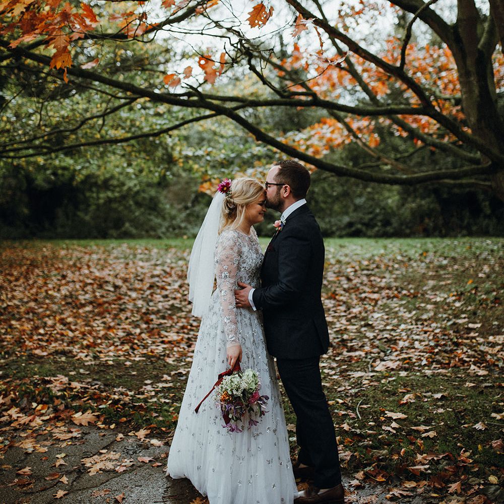 Bride in Bead Embellished Needle &amp; Thread Gown with Cascading Tulle Skirt and Semi Sheer Sleeves | Elbow Length Veil | Bridal Up Do with Pink Hair Flowers | Groom in Check Blue Three Piece Suit by T.M.Lewin with Maroon Tie and Pocket Square | Purple, Orange and Pink Flowers with Foliage and Maroon Trailing Ribbon | Mariachi Band and Persian Rug Aisle for Autumn Wedding | Leah Lombardi Weddings