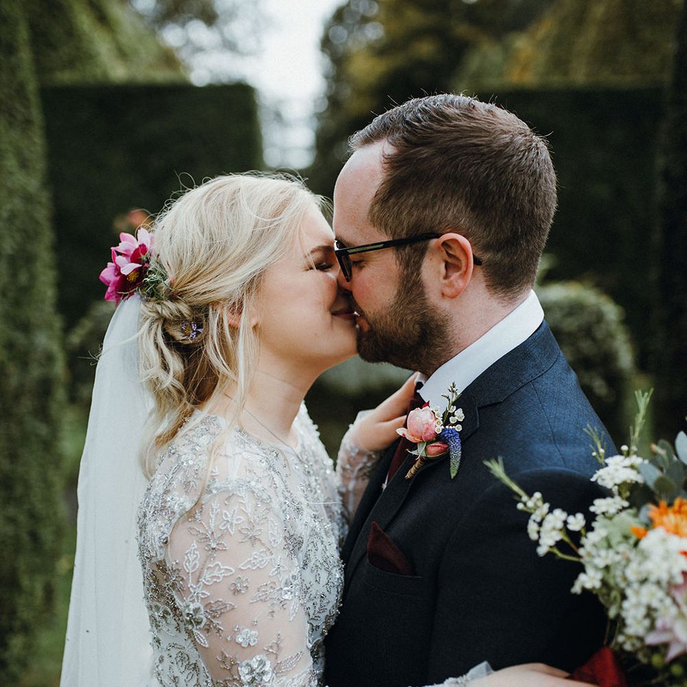 Bride in Bead Embellished Needle &amp; Thread Gown with Cascading Tulle Skirt and Semi Sheer Sleeves | Elbow Length Veil | Bridal Up Do with Pink Hair Flowers | Groom in Check Blue Three Piece Suit by T.M.Lewin with Maroon Tie and Pocket Square | Purple, Orange and Pink Flowers with Foliage and Maroon Trailing Ribbon | Mariachi Band and Persian Rug Aisle for Autumn Wedding | Leah Lombardi Weddings