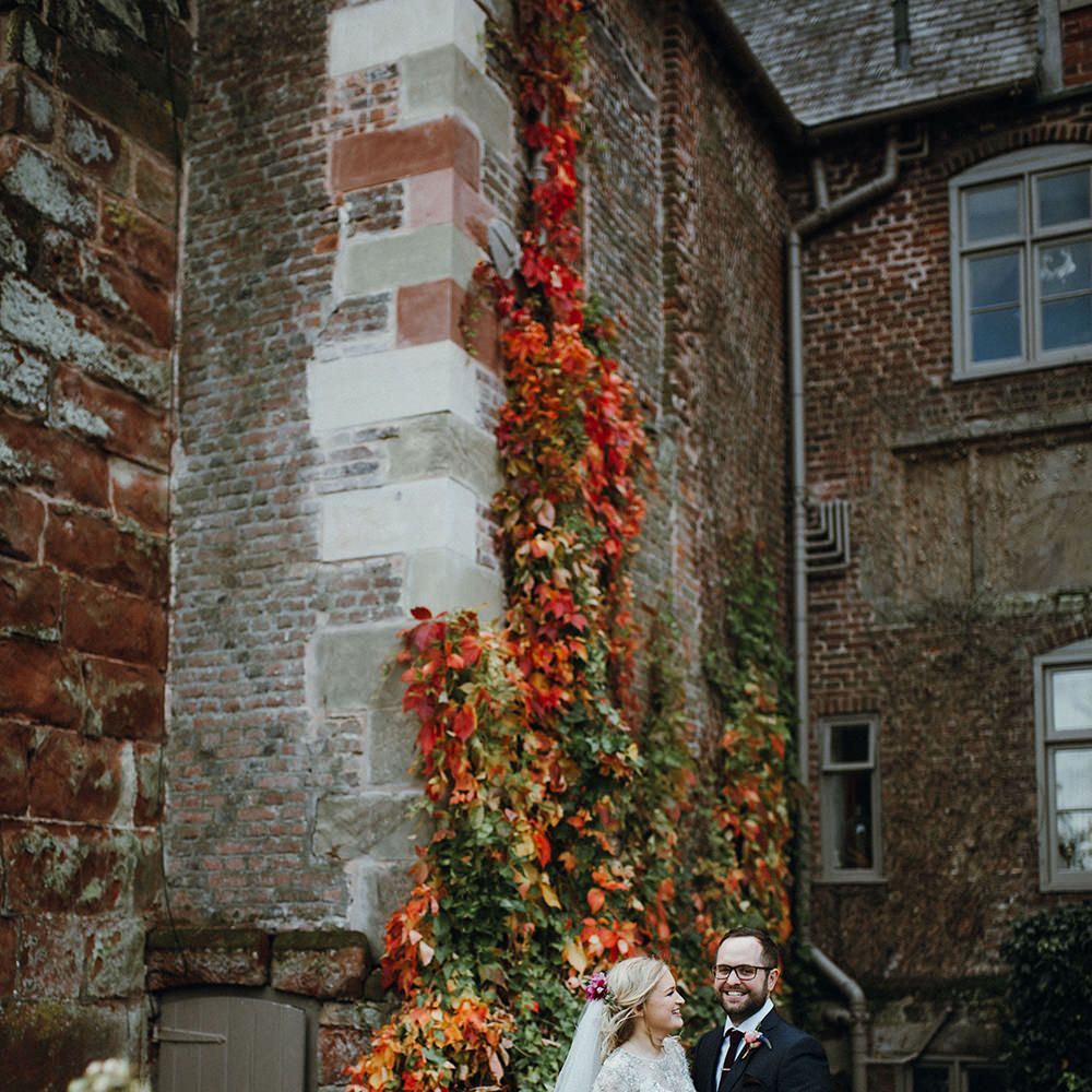 Bride in Bead Embellished Needle &amp; Thread Gown with Cascading Tulle Skirt and Semi Sheer Sleeves | Elbow Length Veil | Bridal Up Do with Pink Hair Flowers | Groom in Check Blue Three Piece Suit by T.M.Lewin with Maroon Tie and Pocket Square | Purple, Orange and Pink Flowers with Foliage and Maroon Trailing Ribbon | Mariachi Band and Persian Rug Aisle for Autumn Wedding | Leah Lombardi Weddings