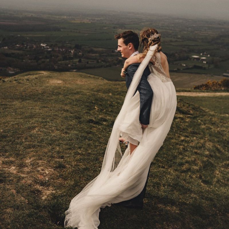 bride on her grooms back in the countryside