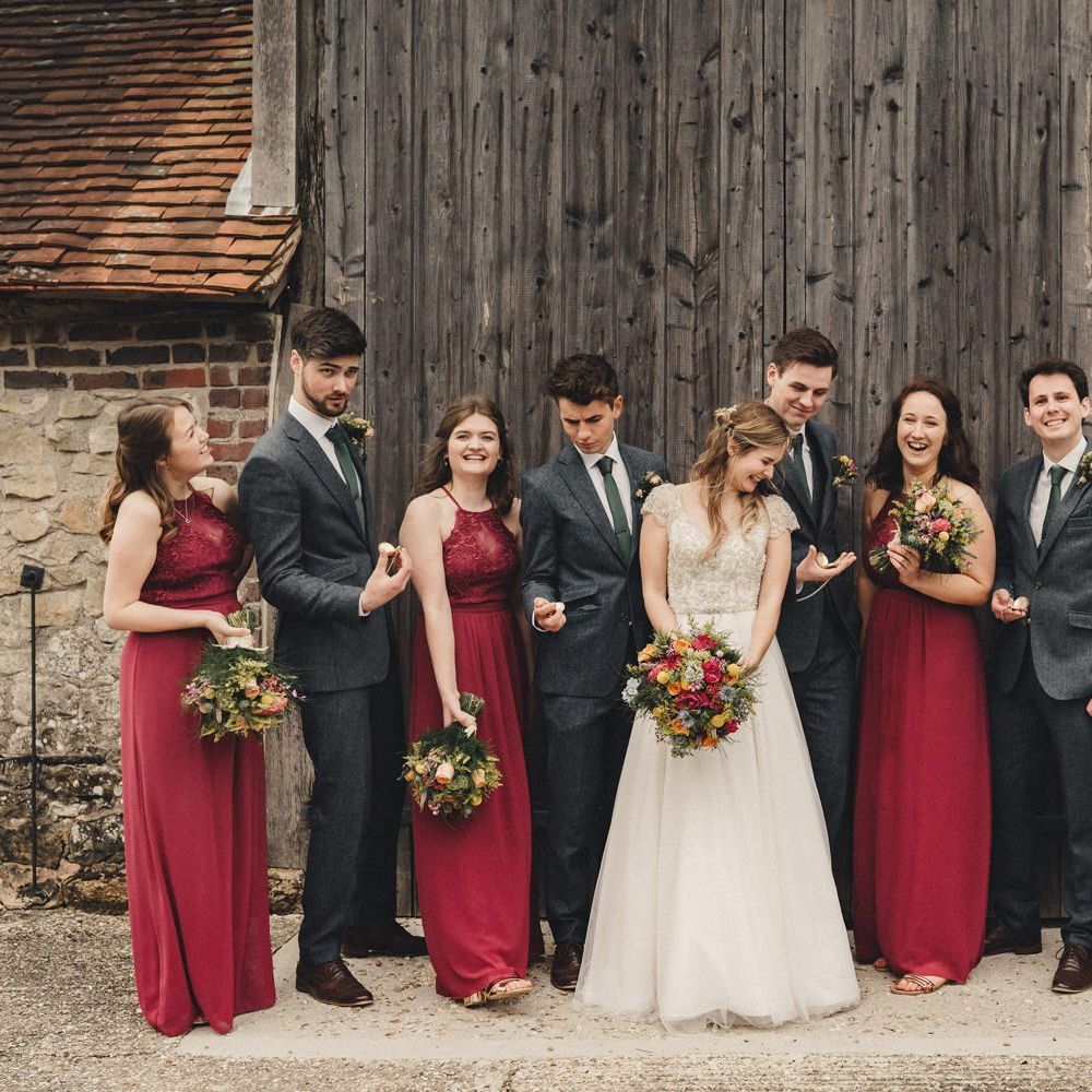 wedding party portrait with bridesmaids in red dresses and groomsmen in dark blue wool suits