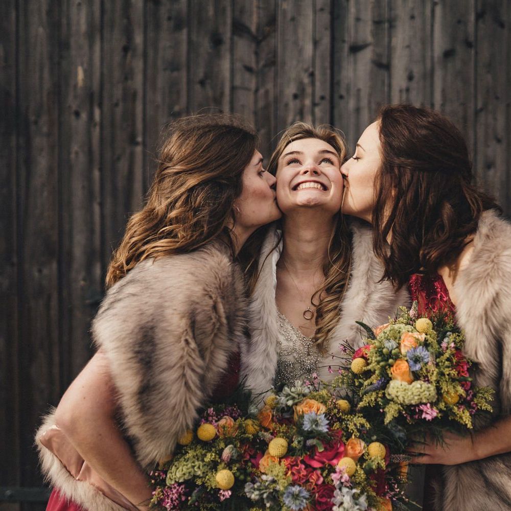 bride with her bridesmaids kissing her cheeks