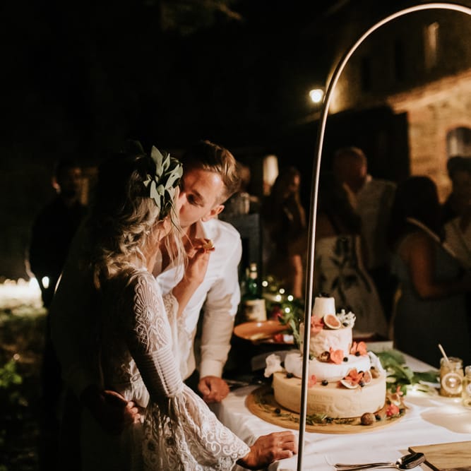 Cutting the Cake | Bride in Spell &amp; the Gypsy Collective Bell Sleeve Wedding Dress | Groom in Chino's &amp; Blazer | Outdoor Bohemian Destination Wedding at La Selva, Tuscany | Damien Milan Photography