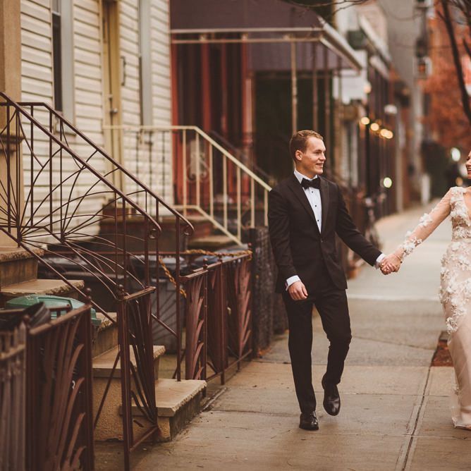 Bride in Marchesa bridal gown holds hands with groom