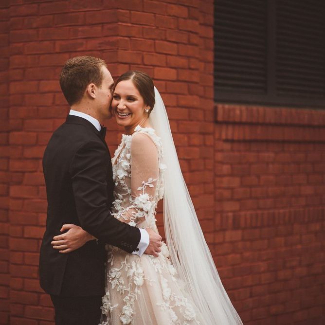 Bride in Marchesa bridal gown hugs groom