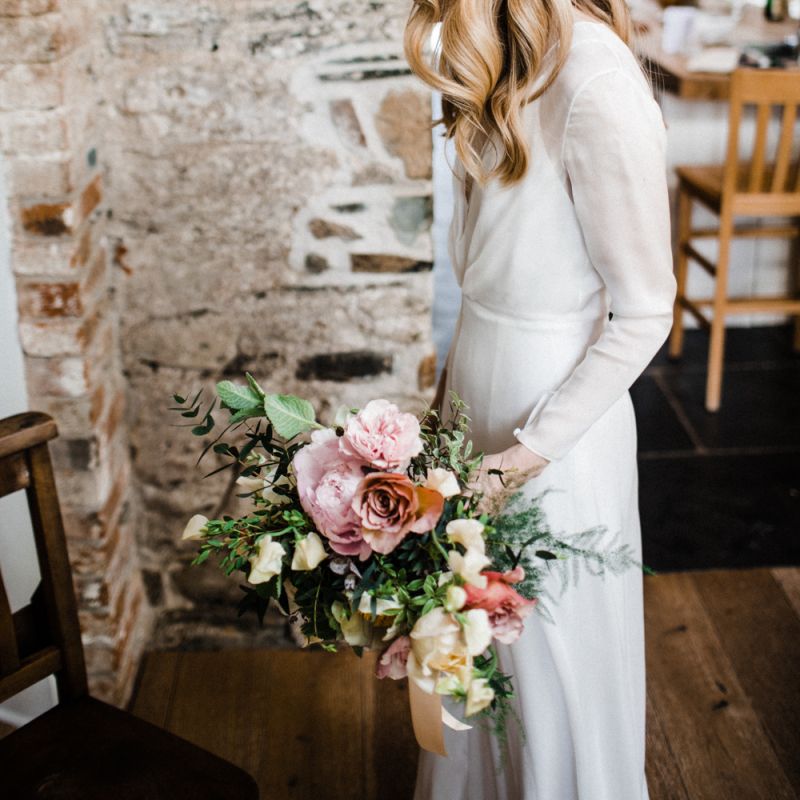 Bride in Andrea Hawkes Wedding Dress with Long Sleeves and Wavy Hair