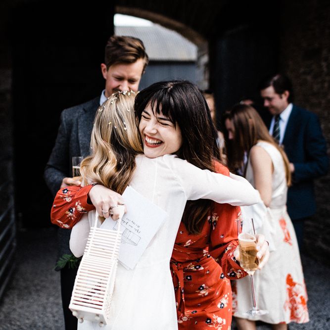 Stylish Wedding Guest in Red Floral Dress and Bangs Hugging The Bride