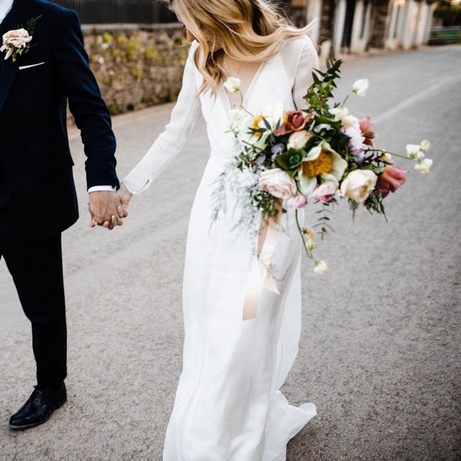 Bride in Andrea Hawkes Wedding Dress and Groom in Navy Suit Holding Hands
