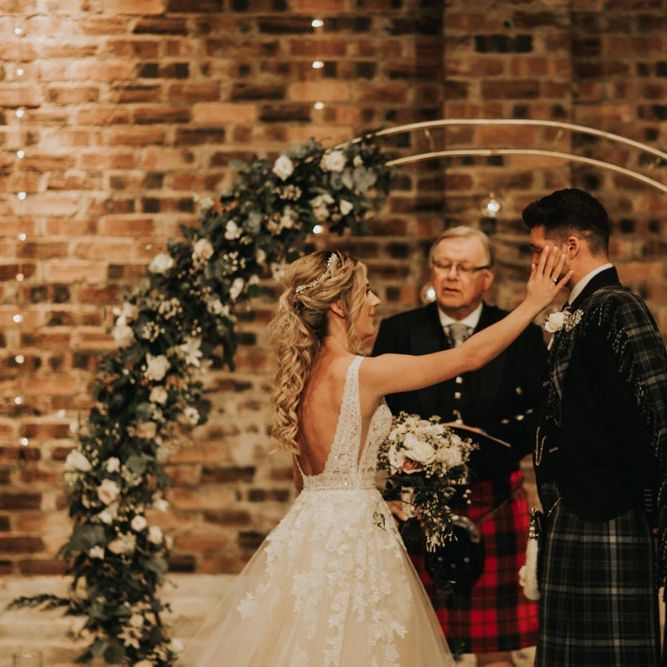 Bride and groom get emotional during ceremony with gold flower arch