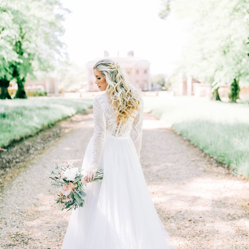 Bride in Lace Wedding Dress Holding White Peony and Peach David Austin Rose Wedding Bouquet and Half up Half Down Wavy Hairstyle
