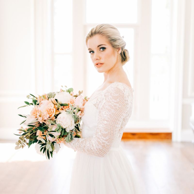 Bride in Lace Long Sleeve Wedding Dress Holding Peach and White Bouquet