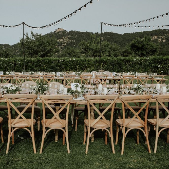 Outdoor Destination Wedding Reception with Wooden Table and Chairs and Festoon Lights