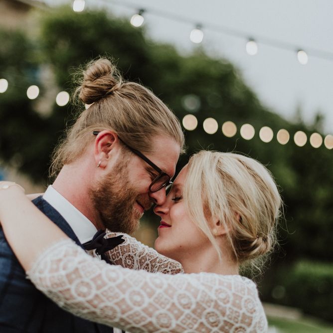 Bride in Lace Long Sleeve Rembo Styling Wedding Dress and Groom in Navy Check Blazer Embracing