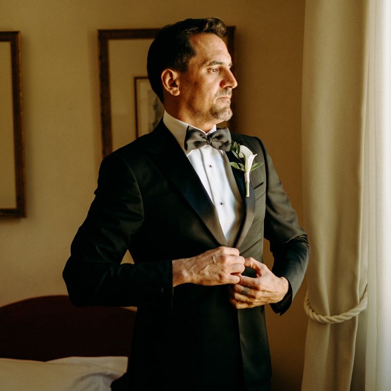 Groom preparations in black tie wedding suit