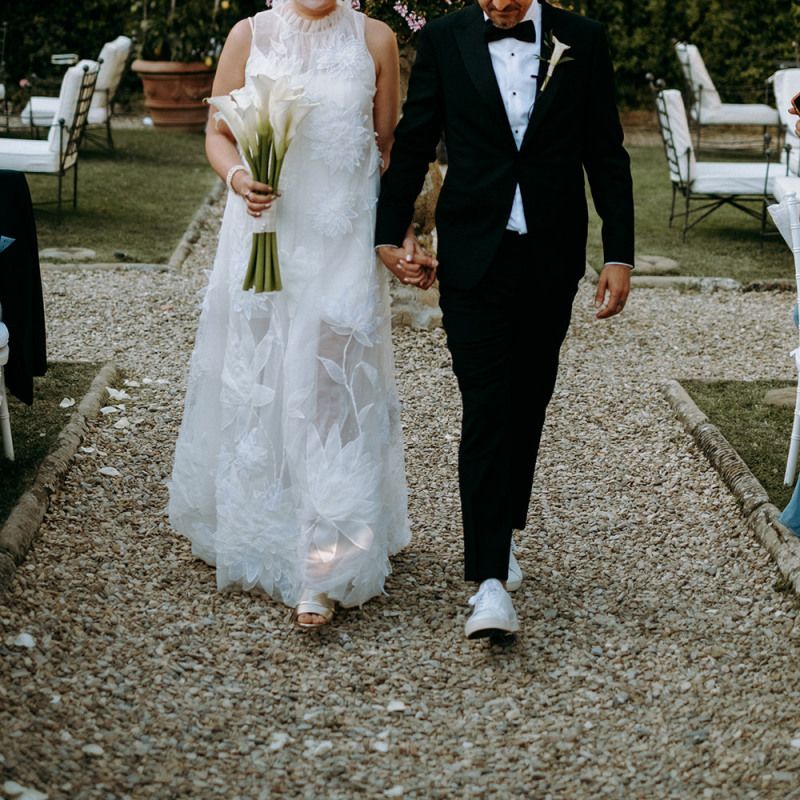 Bride in 3D flower wedding dress from Viktor &amp; Rolf with groom in tuxedo and trainers
