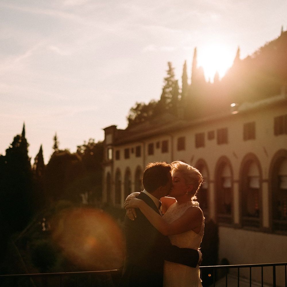 Bride and groom kiss in front of sunset in Italy
