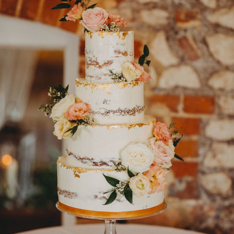 Beautiful semi naked wedding cake with copper detail and floral decor