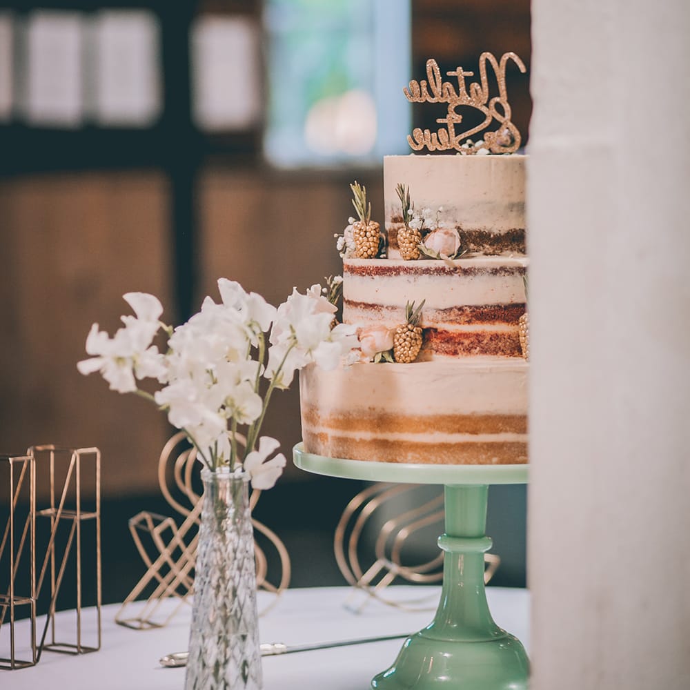 Semi Naked Wedding Cake Decorated with Pastel Flowers and Gold Painted Blackberries |  Pastel Green Cake Stand | Halterneck Maggie Sottero Dress and Garden Games at Gate Street Barn | Story + Colour Photography