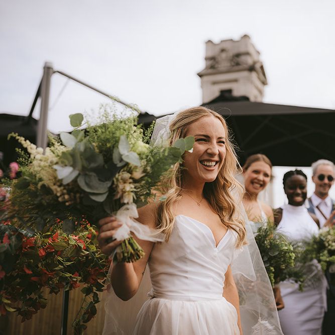 Bride in Bespoke Wedding Gown with Blush Underskirt and One Off Shoulder Strap | Fingertip Length Veil Customised with Feathers | Half Up Half Down Bridal Hair | Astrid &amp; Miyu Necklace | Homemade Bouquet of White Flowers, Ferns and Foliage | Bike Shed Motorcycle Club Wedding for ELLE Digital Editor | Nigel John Photography