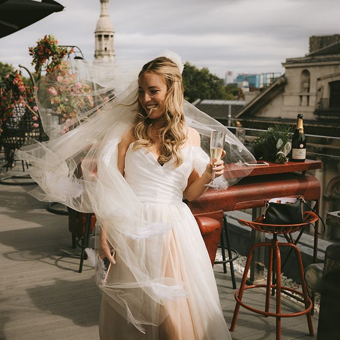 Pre-Ceremony Champagne | Bride in Bespoke Wedding Gown with Blush Underskirt and One Off Shoulder Strap | Fingertip Length Veil Customised with Feathers | Half Up Half Down Bridal Hair | Bike Shed Motorcycle Club Wedding for ELLE Digital Editor | Nigel John Photography