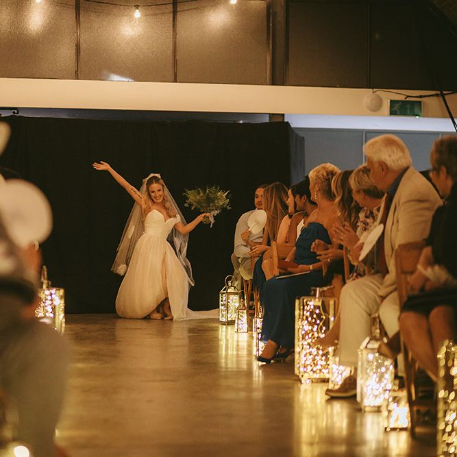 Entrance of the Bride | Bespoke Wedding Gown with Blush Underskirt and One Off Shoulder Strap | Fingertip Length Veil Customised with Feathers | Half Up Half Down Bridal Hair | Nude Topshop Shoes with Pom Pom | Homemade Bouquet of White Flowers, Ferns and Foliage | Lanterns Filled with Fairylights | Bike Shed Motorcycle Club Wedding for ELLE Digital Editor | Nigel John Photography