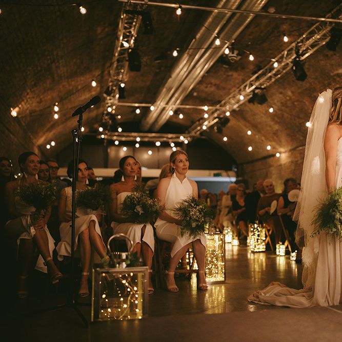 Wedding Ceremony | Bride in  Bespoke Wedding Gown with Blush Underskirt and One Off Shoulder Strap | Fingertip Length Veil Customised with Feathers | Nude Topshop Shoes with Pom Pom | Homemade Bouquet of White Flowers, Ferns and Foliage | Groom in Grey Puppy Tooth Check Two-Piece Paul Smith Suit with Amber Tie Pin, Pocket Square and Braces | Lanterns Filled with Fairylights | Festoon Lights | Bike Shed Motorcycle Club Wedding for ELLE Digital Editor | Nigel John Photography