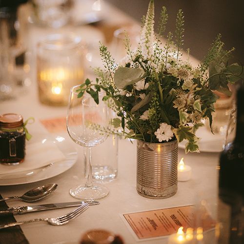 Wedding Reception Décor | Wooden Trestle Tables with White Runner | White Flowers, Ferns and Foliage in Tin Can | Tea Lights | Bike Shed Motorcycle Club Wedding for ELLE Digital Editor | Nigel John Photography