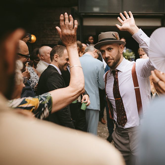 Groom in Grey Puppy Tooth Check Two-Piece Paul Smith Suit with Amber Tie Pin, Pocket Square, Braces and Hat with Feather | Bike Shed Motorcycle Club Wedding for ELLE Digital Editor | Nigel John Photography