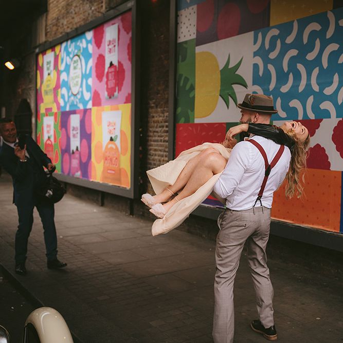 Groom in Grey Puppy Tooth Check Two-Piece Paul Smith Suit with Amber Tie Pin, Pocket Square, Braces and Hat with Feather | Bride in Bespoke Wedding Gown with Blush Underskirt and One Off Shoulder Strap | Thug Wife Leather Bridal Jacket | Bike Shed Motorcycle Club Wedding for ELLE Digital Editor | Nigel John Photography
