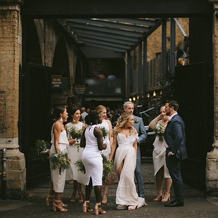 Bride in Bespoke Wedding Gown with Blush Underskirt and One Off Shoulder Strap | Nude Topshop Shoes with Pom Pom | Bridesmaids in Mismatched White Dresses | Bridesmen in Blue Suits | Homemade Bouquets of White Flowers, Ferns and Foliage | Bike Shed Motorcycle Club Wedding for ELLE Digital Editor | Nigel John Photography