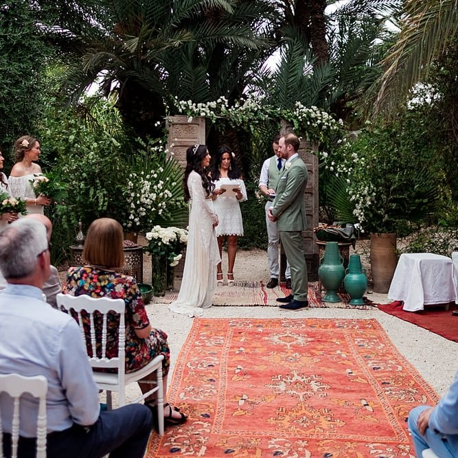 Outdoor Wedding Ceremony | Moroccan Rugs, Wooden Door Altar Wedding Decor | Bride in Rue de Seine Bridal Gown | Groom in Green Beggars Run Suit | Paradise Destination Wedding at Jnane Tamsna in Marrakech, Morocco | Nordica Photography | Matteo Castelluccia Film