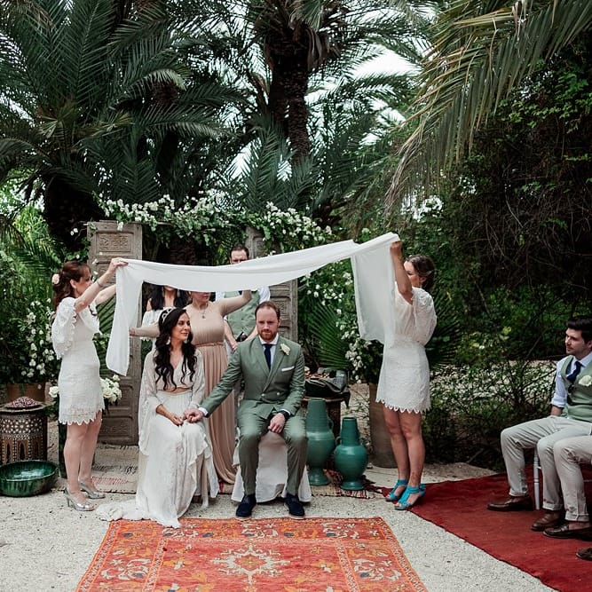 Outdoor Wedding Ceremony | Moroccan Rugs, Wooden Door Altar Wedding Decor | Bride in Rue de Seine Bridal Gown | Groom in Green Beggars Run Suit | Paradise Destination Wedding at Jnane Tamsna in Marrakech, Morocco | Nordica Photography | Matteo Castelluccia Film