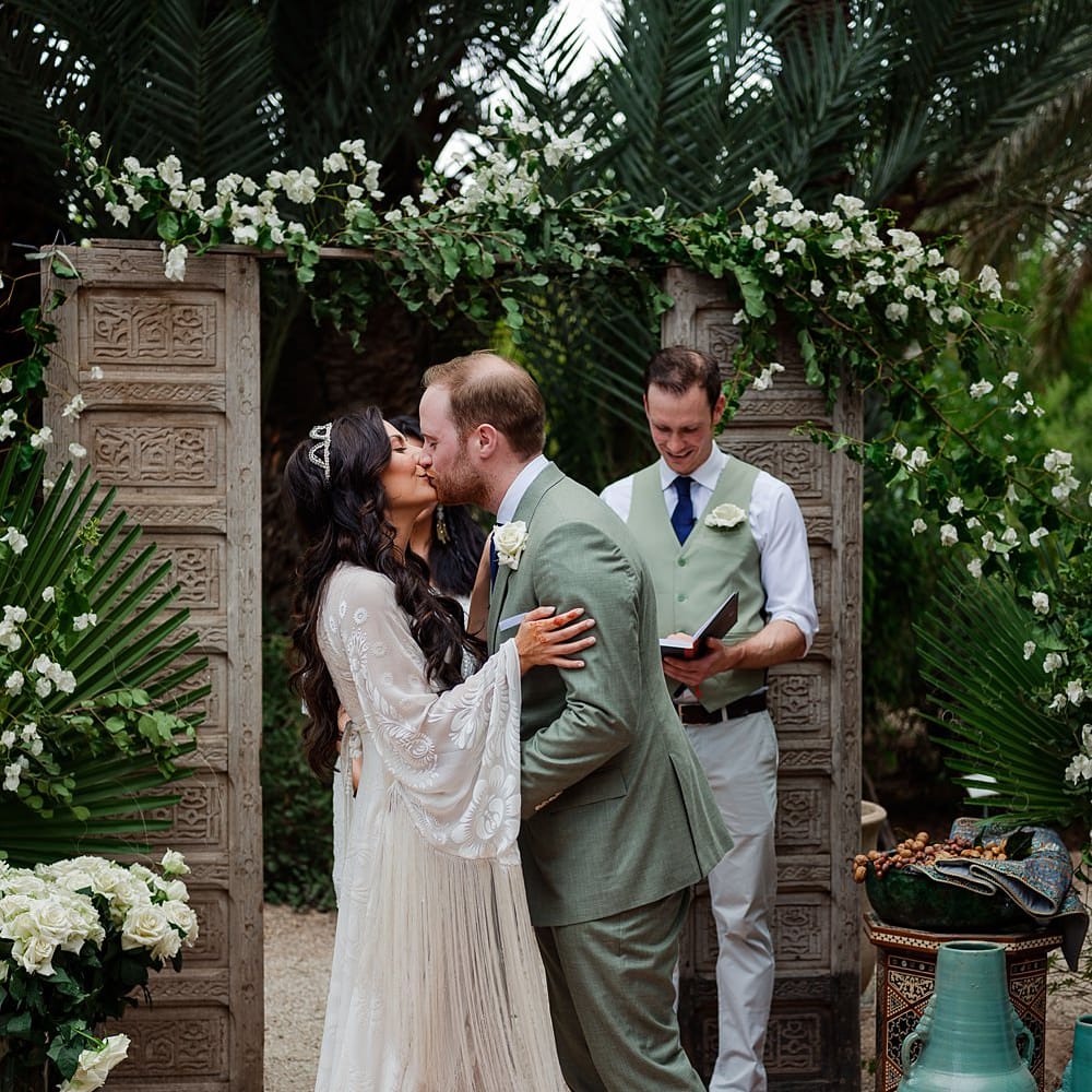 Outdoor Wedding Ceremony | Moroccan Rugs, Wooden Door Altar Wedding Decor | Bride in Rue de Seine Bridal Gown | Groom in Green Beggars Run Suit | Paradise Destination Wedding at Jnane Tamsna in Marrakech, Morocco | Nordica Photography | Matteo Castelluccia Film