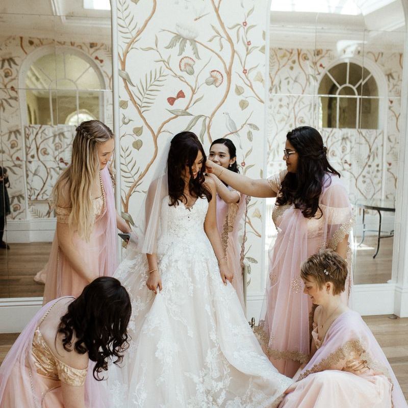 Bride in strapless wedding dress with bridal party in pink saris