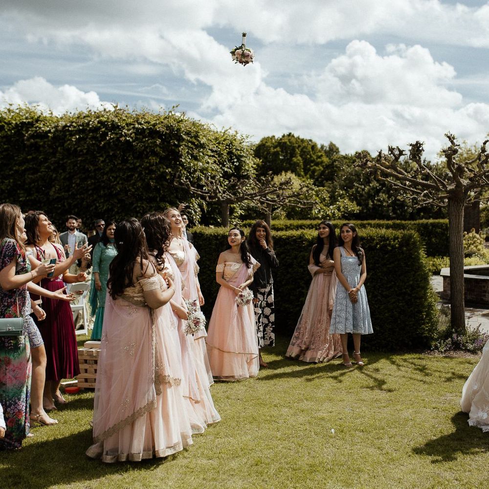 Bride throws bouquet to bridal party in sari dresses