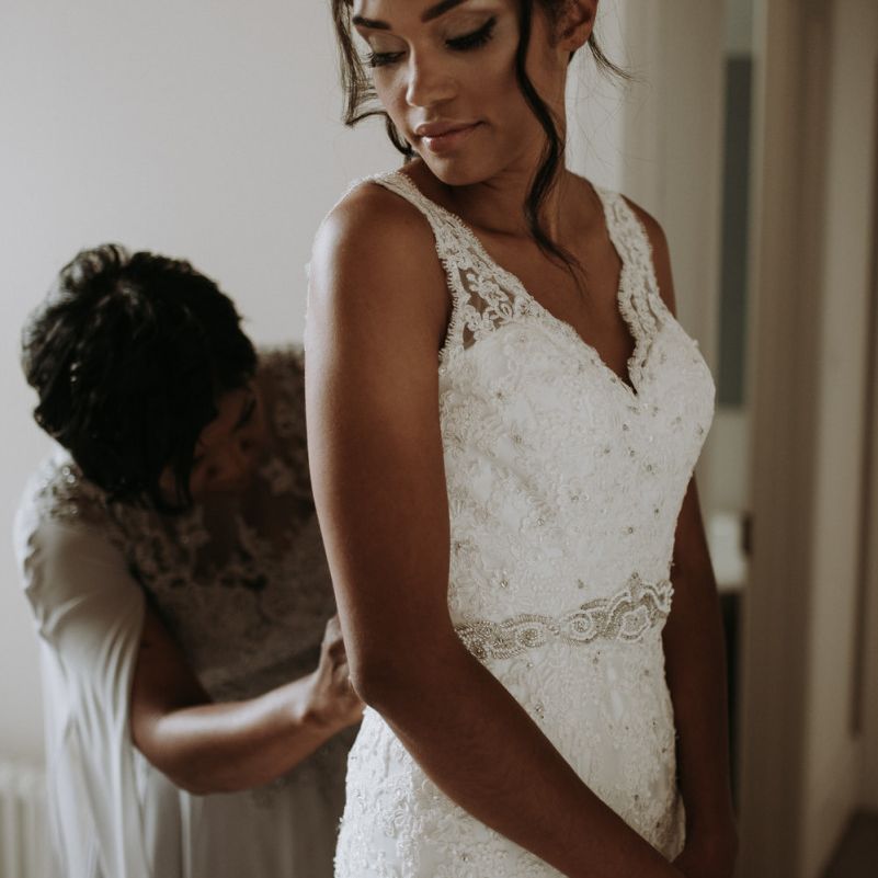 Bride putting on her dress on wedding morning