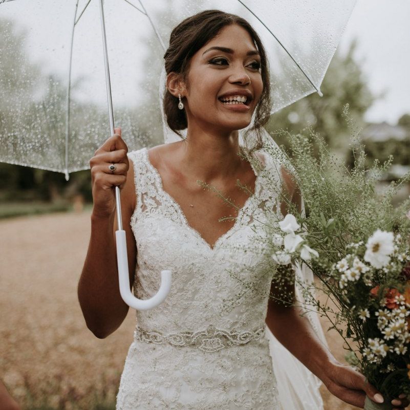 Bride in lace wedding dress holding  a clear umbrella