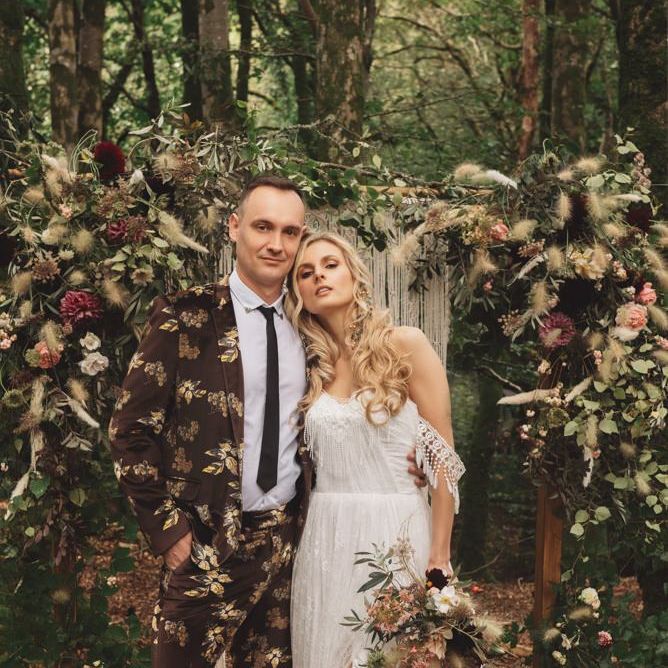 Groom in Brown Patterned Suit and Bride  Cold Shoulder Wedding Dress and Black Lace Boots
