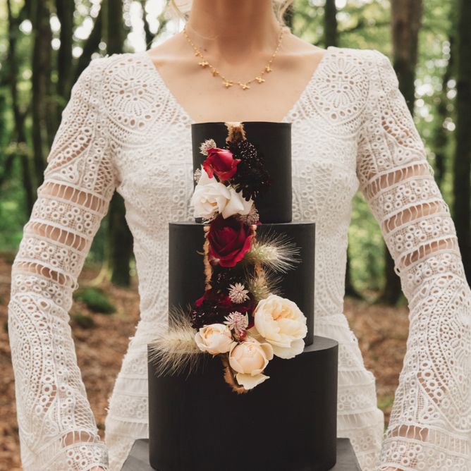 Bride in Lace Wedding Dress Holding a Black Wedding Cake