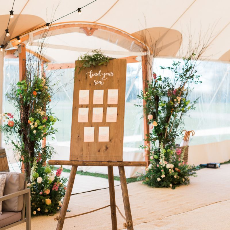 Wooden Table Plan on an Easel with Festoon Lights &amp; Floral Decor