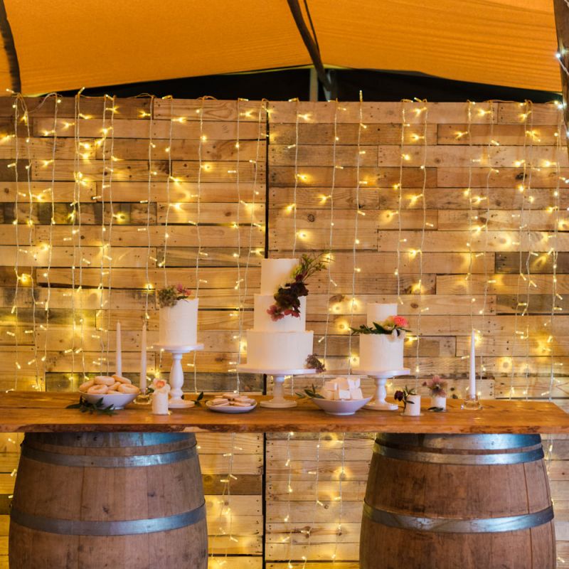 Cake Table on Barrels with String Lights Backdrop
