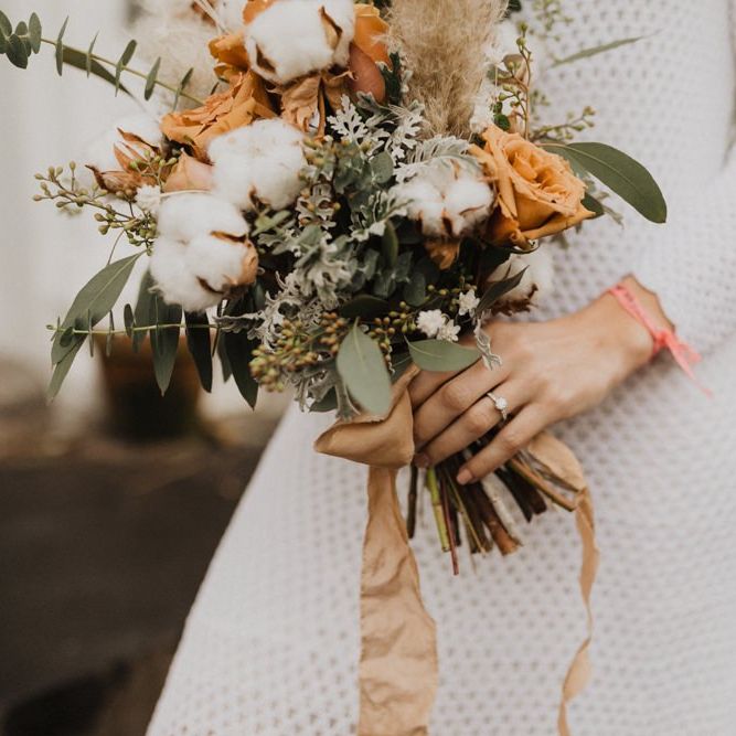Bride wearing vintage dress and neutral bouquet with cotton flowers and foliage