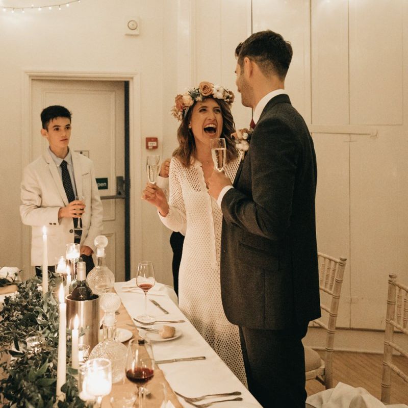 Bride and groom toast at intimate reception with foliage table decor and taper candles