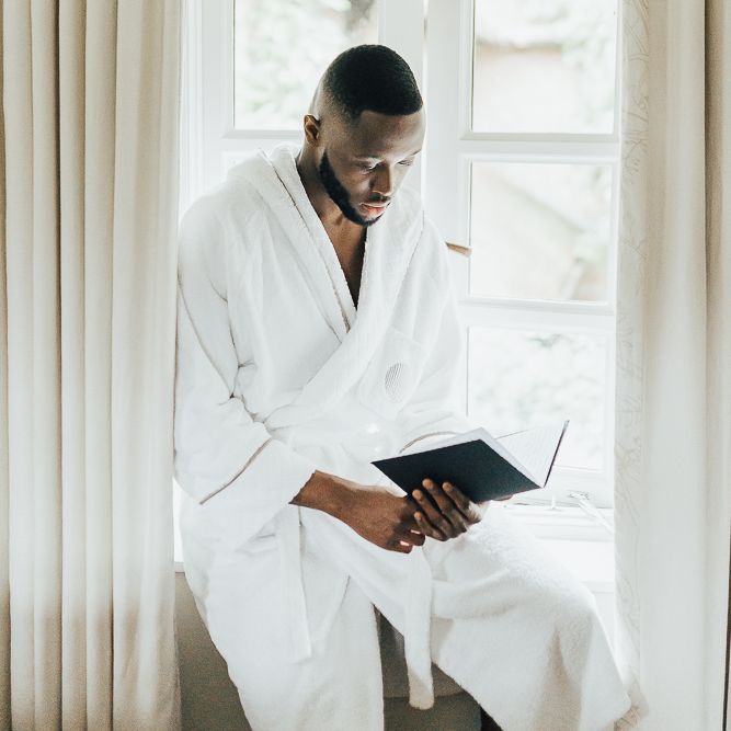 Groom in white robe on wedding morning writing his vows