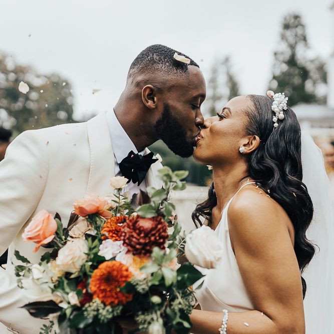 Bride and groom kissing at the end of the confetti line